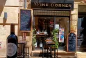 Vetrina del Wine Corner, enoteca a Bordeaux, con bottiglie di vino esposte, tavoli alti all'aperto e cartelli promozionali.
