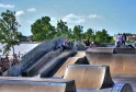 Skate park di Bordeaux con rampe in cemento, pattinatori e spettatori, vista sulla Garonna e l'architettura della città