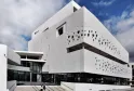 Facciata bianca moderna del Museo del Mare di Bordeaux con perforazioni circolari, scale di accesso e cielo blu sullo sfondo