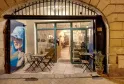 Vetrina della enoteca Levain Le Vin a Bordeaux, con terrazza esterna arredata di sedie pieghevoli, vetrine illuminate e manifesto promozionale blu